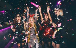 How much should you spend on a bachelor party. Ladies with hands in hair dancing as confetti falls around them