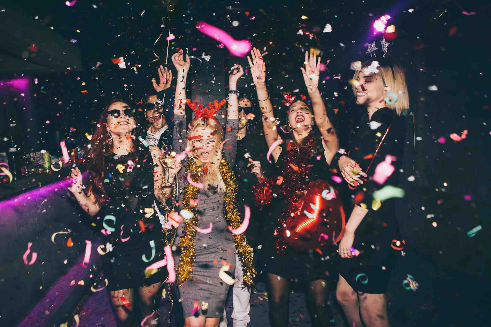How much should you spend on a bachelor party. Ladies with hands in hair dancing as confetti falls around them