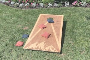 Game of cornhole on grass in backyard at party