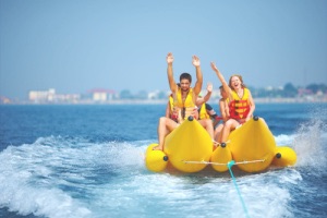 Friends on banana boat throwing arms in air enjoying themselves