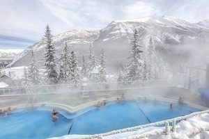 People hanging out in blue hot springs pool overlooking Rundle Mountain