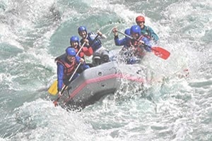 Group in white water raft splashing through river