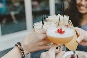 Group of friends with passionfruit martinis toasting drinks in centre