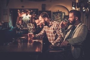 Friends laughing and enjoying beer while sitting at bar