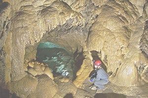 People climbing through cave on ropes