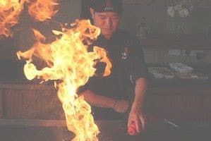Teppanyaki chef frying meats in flames