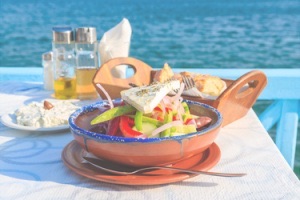 Close up of fresh Greek salad served in terracotta pool on table overlooking water