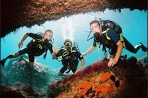 3 people with diving equipment posing for camera in underwater cave