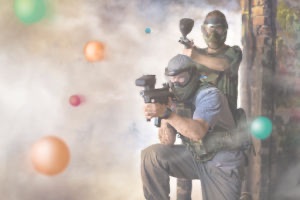 Man and woman in camoflauge outfits with paintball guns ready to fire at opponents