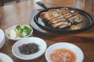 Close up of meats on Japanese grill with sauces in side bowls