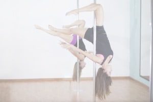 Girl hanging upside down on pole in studio