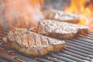 Steak sizzling on grill with flames
