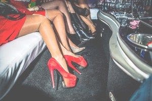 Close of women's legs with red high heels in limo