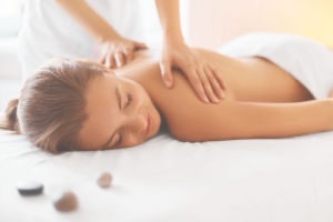 Woman lying on back enjoying relaxing massage from masseuse