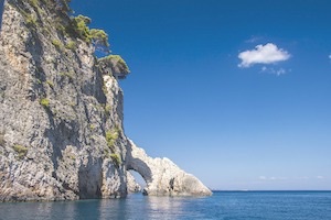 Cliffside with caves underneath and blue waters and blue sky