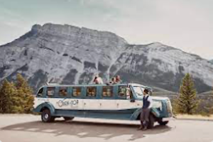 1930's style stretched bus parked in front of Banff's iconic Rundle Mountain