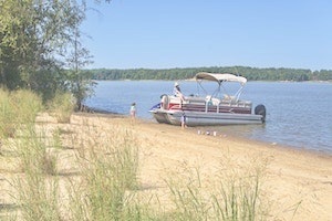 Pontoon boat parked against lakeside beach