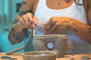 Woman putting layers of clay together building bowl