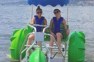 Two girls smiling onboard water trike with bright green wheels