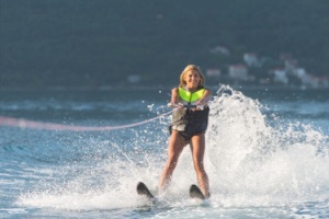 Girl smiling on two water skis being pulled behind speed boat