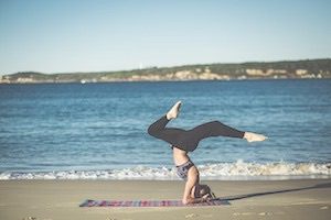Girl holding yoga pose on colourful mat on beach