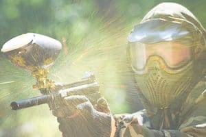 Close up of man in paintball helmet shooting paintball gun
