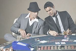 Two men looking at cards around poker table