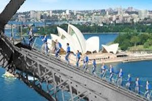 People climbing up Sydney harbour bridge with Opera House in background