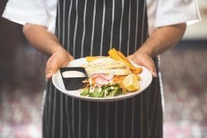 Chef holding meal on plate he has just prepared.