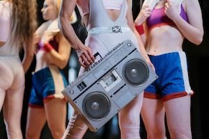 Person in 80s aerobics gear holding boom box stereo