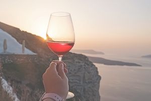 Woman holding a wine glass while looking at a view in Santorini